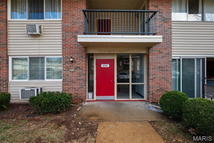 View of exterior entry with brick siding and a wall mounted AC