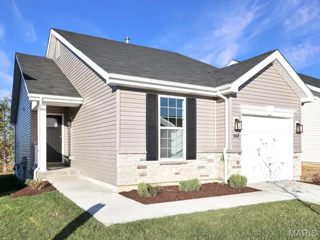 View of front of home with stone siding, an attached garage, a shingled roof, concrete driveway, and a front lawn