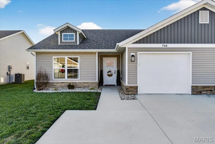 View of front of home featuring stone siding, a shingled roof, a front lawn, concrete driveway, and an attached garage