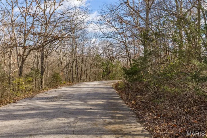 View of asphalt street featuring a view of trees