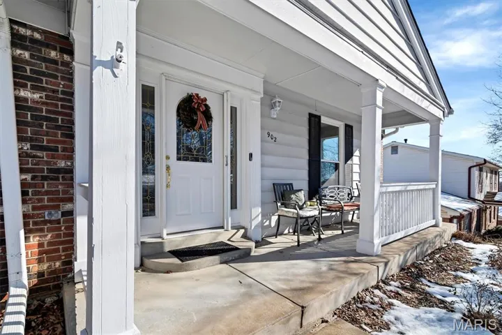 Property entrance featuring covered porch and brick siding