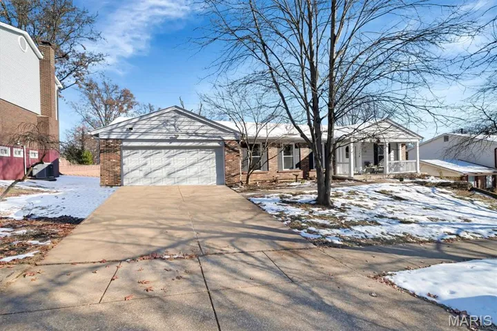 View of front of property with driveway, a porch, a garage, and brick siding