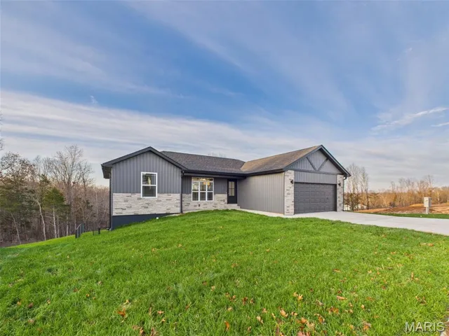View of front facade featuring concrete driveway, an attached garage, a front lawn, brick siding, and a shingled roof