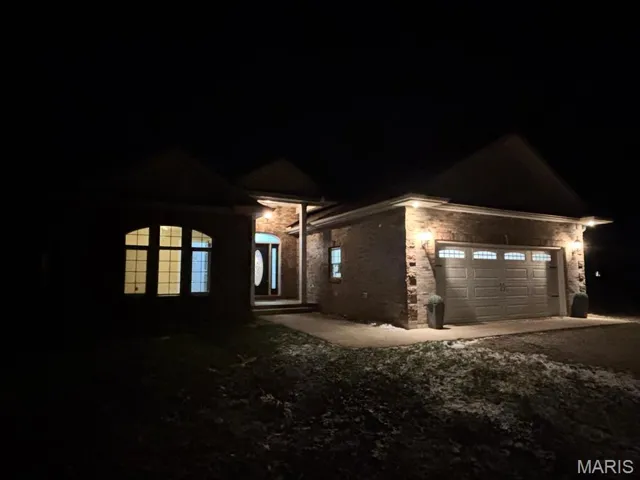 View of front of house featuring stone siding, driveway, and a garage