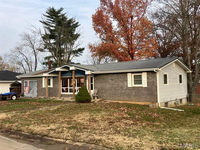View of front of home featuring brick siding, a front lawn, and a metal roof