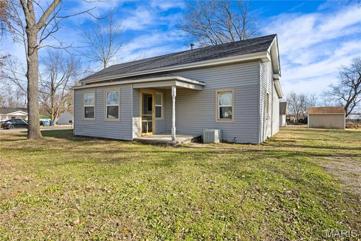 Back of house featuring a yard, roof with shingles, and an outdoor structure