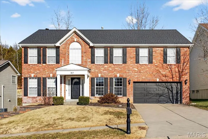 Colonial-style house with concrete driveway, brick siding, and a garage
