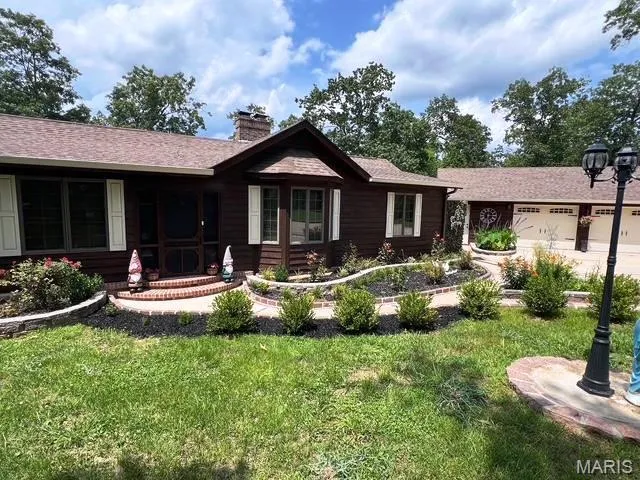 View of front of property with a front yard, a chimney, an attached garage, and a shingled roof