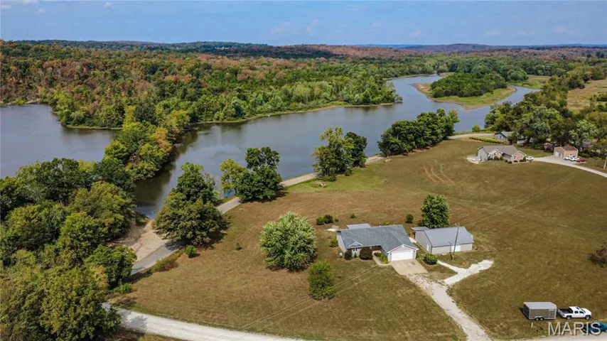 Aerial overview of property's location with a heavily wooded area and a large body of water