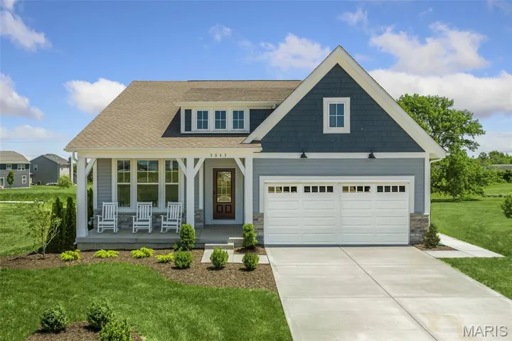 Craftsman-style home featuring covered porch, a front lawn, a shingled roof, and driveway