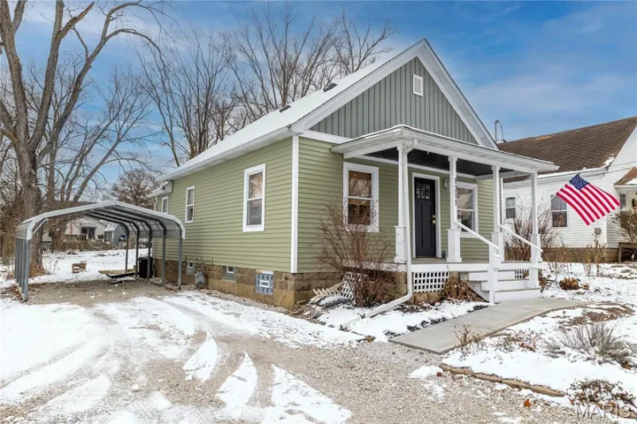 View of front of property featuring a carport, a porch, and board and batten siding