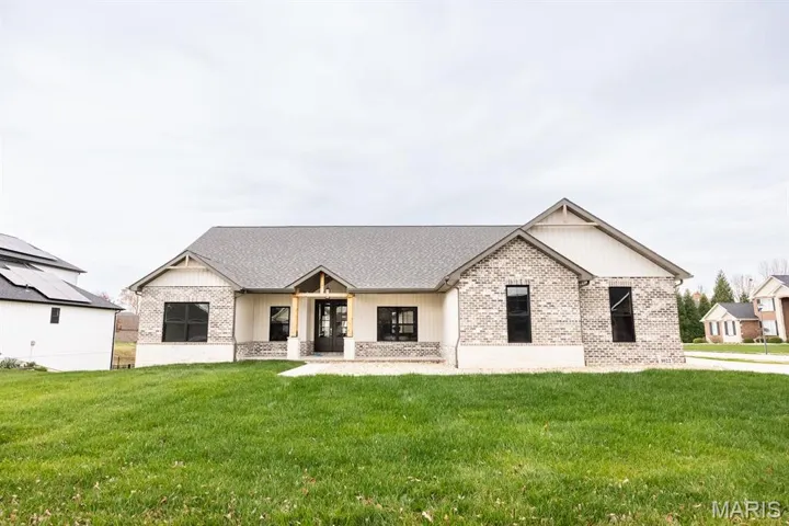 Modern inspired farmhouse with a porch, a front yard, and brick siding
