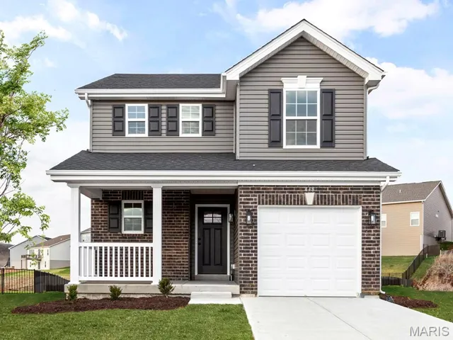 View of front of property with covered porch, a garage, and a front lawn