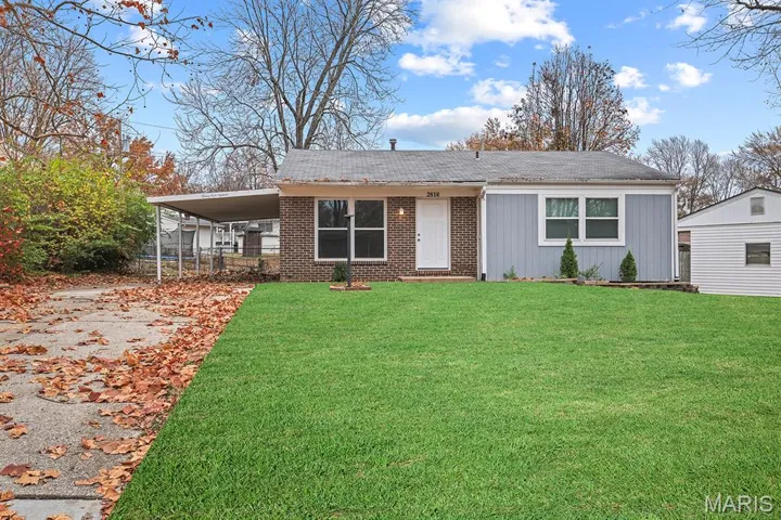 View of front of home featuring a front lawn, driveway, an attached carport, roof with shingles, and brick siding