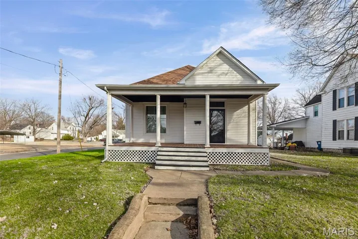 View of front facade with covered porch, a front yard, and a shingled roof
