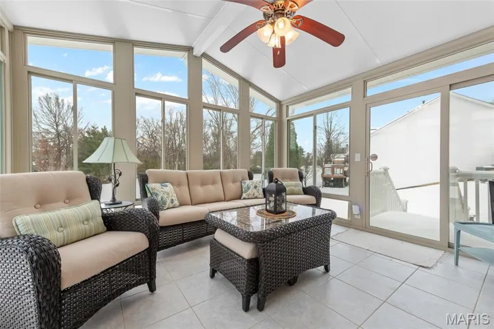 Sunroom featuring tile patterned floors, beam ceiling, expansive windows, and high vaulted ceiling