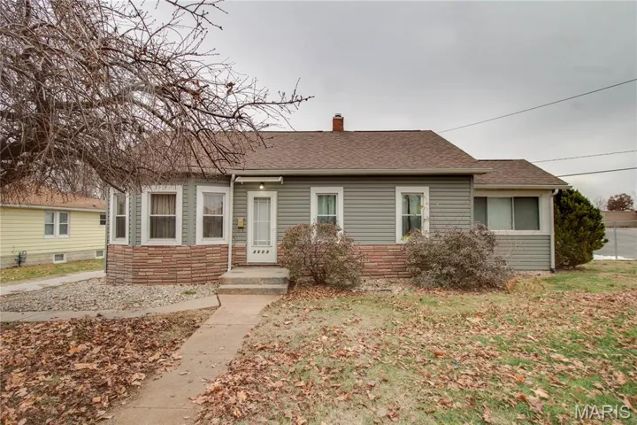 View of front of property featuring stone siding, roof with shingles, and a chimney