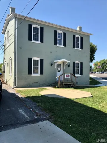 View of front of house with a chimney, a front lawn, and brick siding