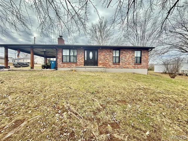 Ranch-style home with brick siding, an attached carport, a chimney, and a front yard
