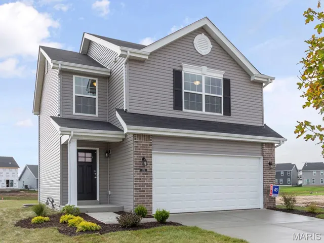 Traditional home featuring brick siding, a garage, and driveway