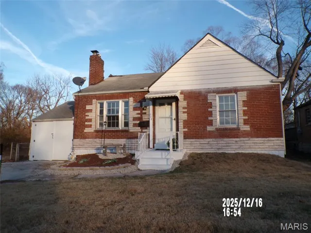 Bungalow featuring a front yard, a chimney, and brick siding
