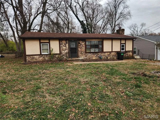 View of front of property with a chimney, stone siding, and stucco siding