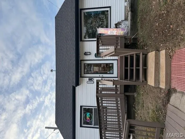 View of front facade featuring roof with shingles and a deck