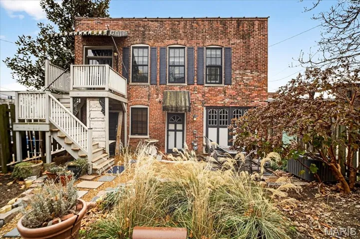 Carriage House Entry-located in the Rear view of property featuring a balcony, brick siding, and stairway