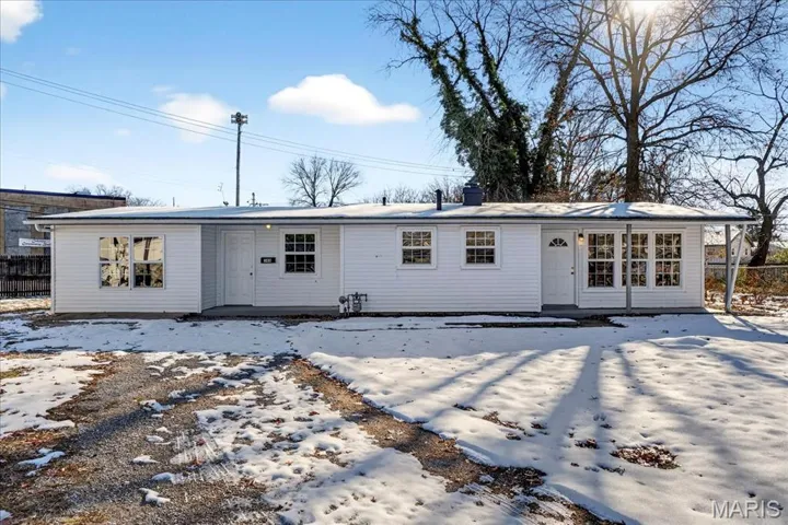Snow covered back of property with a patio and a chimney
