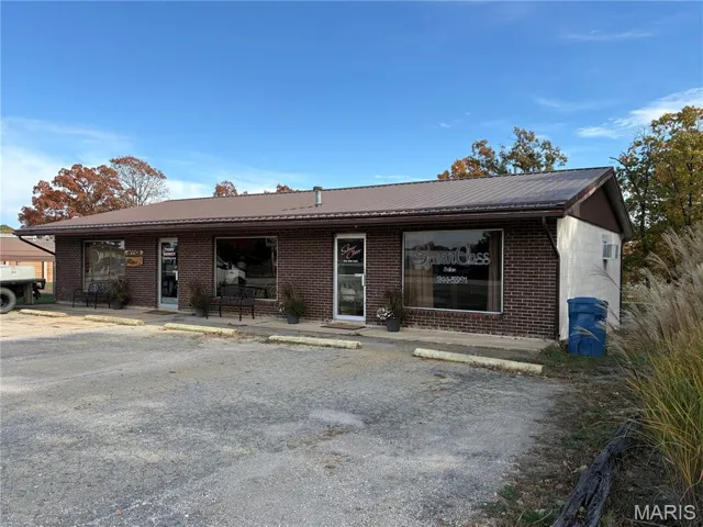 Single story home featuring brick siding, a metal roof, a porch, and uncovered parking