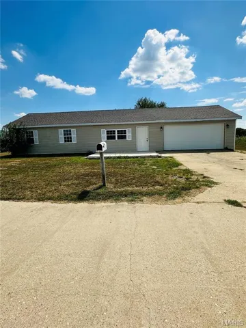 Ranch-style home featuring concrete driveway, a front yard, and a garage