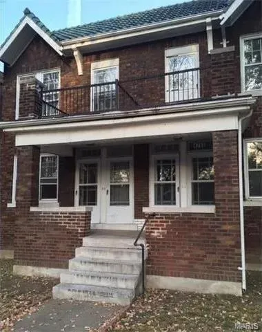 Doorway to property with brick siding, a tiled roof, and a porch