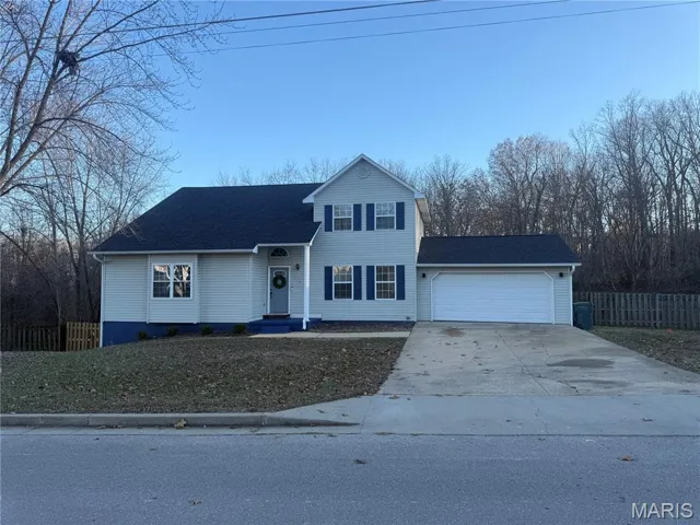 Traditional-style house with driveway, roof with shingles, and an attached garage