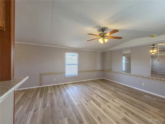 Living room featuring vaulted ceiling, light wood-type flooring, and ceiling fan