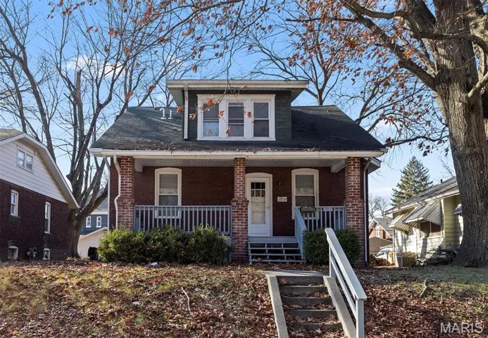 Bungalow-style house featuring covered porch, brick siding, and a shingled roof