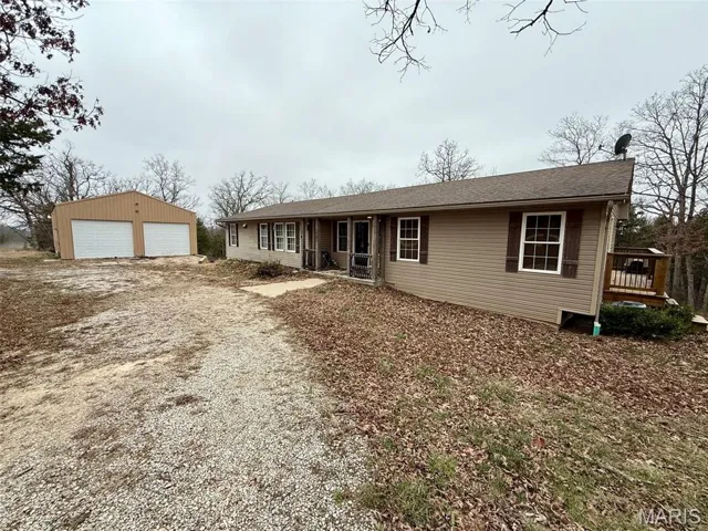 Ranch-style home with an outdoor structure, a detached garage, a shingled roof, and driveway