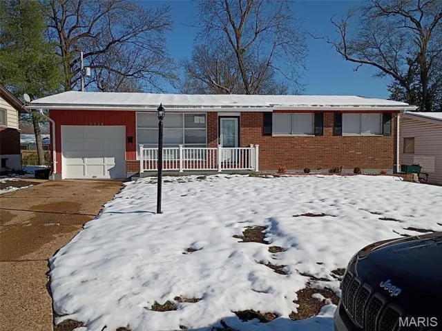 Single story home with brick siding, an attached garage, and driveway