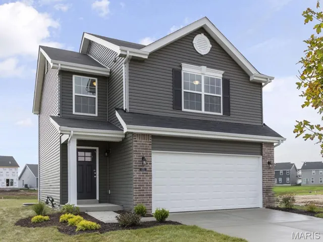 View of front facade featuring brick siding, a garage, and concrete driveway