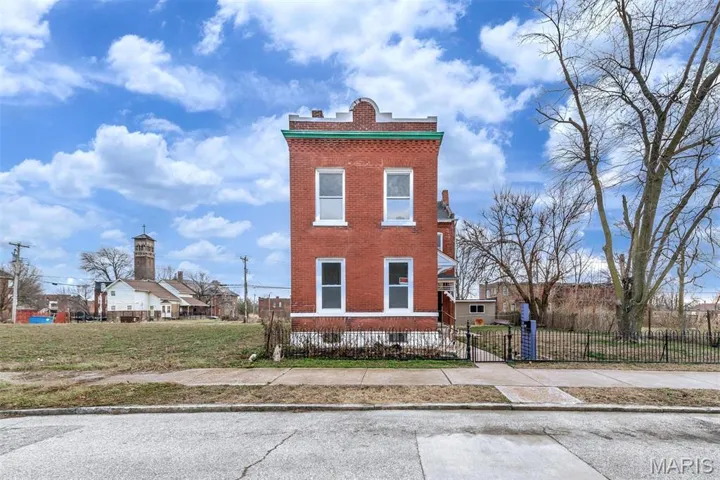 View of front facade featuring brick siding, a fenced front yard, and a chimney