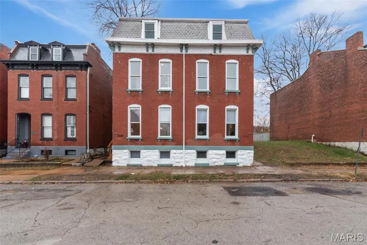 View of front facade featuring mansard roof and brick siding
