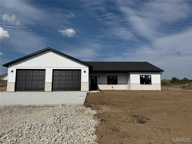 View of front of home with stone siding, concrete driveway, an attached garage, and roof with shingles