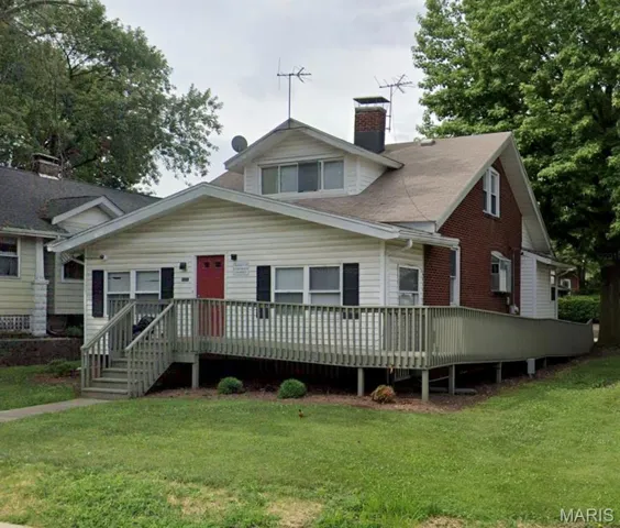 Bungalow-style home featuring a deck, a chimney, a front yard, and roof with shingles