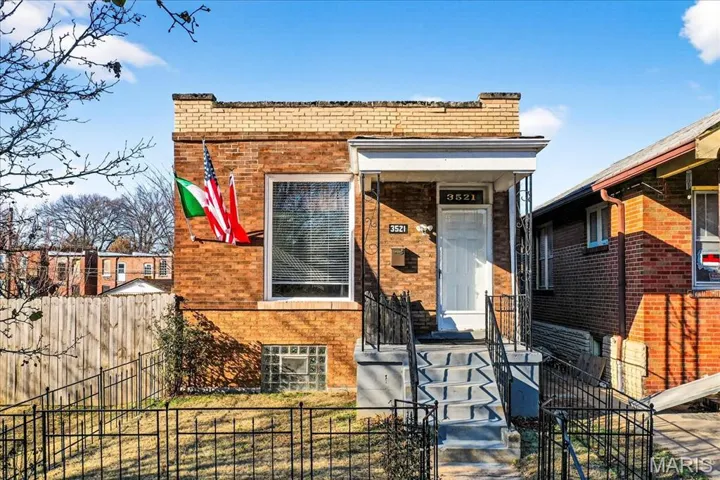 View of front of home featuring brick siding, a fenced front yard, and a gate
