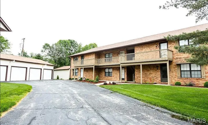 Front of property with a balcony, an outbuilding, a front lawn, and brick siding