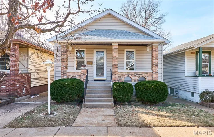 View of front of property featuring covered porch, brick siding, and a shingled roof