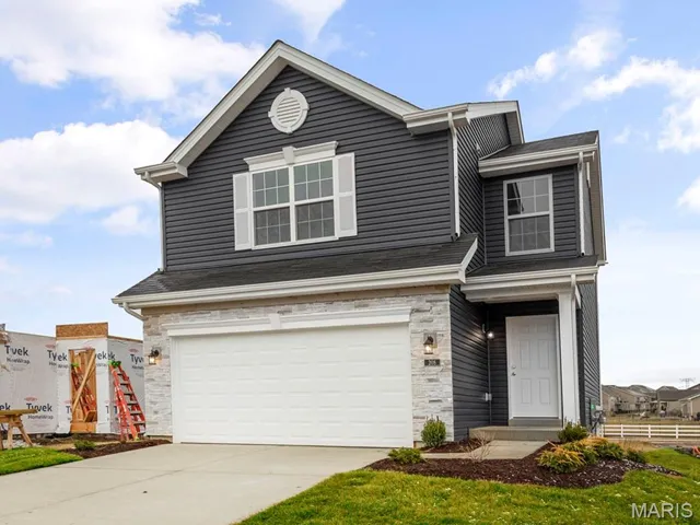 View of front facade featuring stone siding, a garage, and driveway