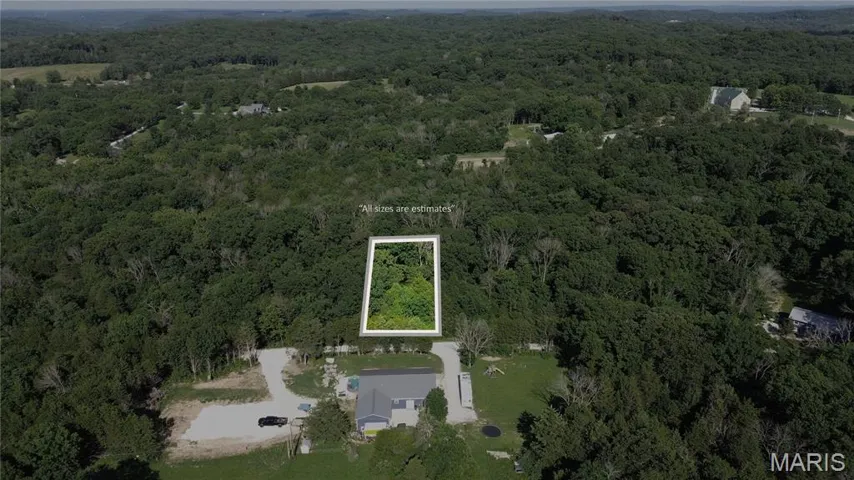 Aerial overview of property's location with property parcel outlined and a heavily wooded area