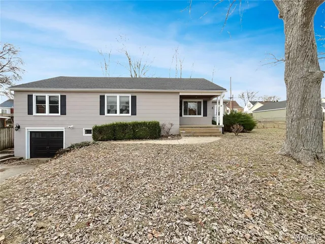View of front of home with covered porch, roof with shingles, a garage, and driveway