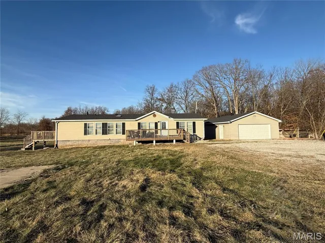 Manufactured / mobile home with a deck, a garage, a front yard, and an outbuilding