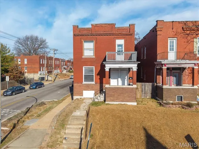Traditional-style house featuring a balcony, brick siding, and a residential view